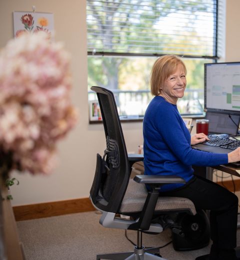 Woman working at computer with flowers in foreground
