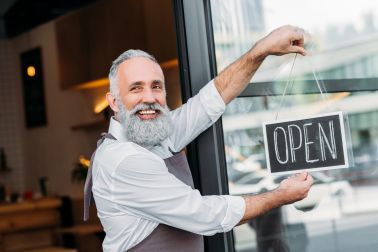 Senior man hanging open sign for small business